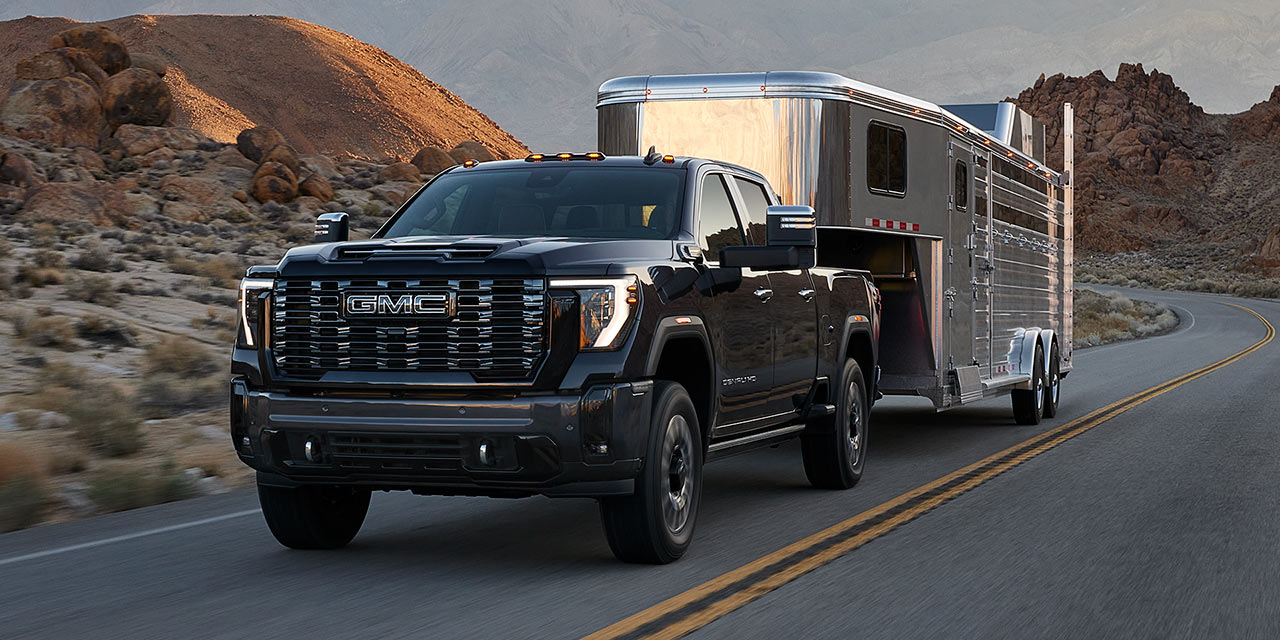 The GMC Sierra HD Heavy Duty Truck Driving Down the Road Towing a Trailer