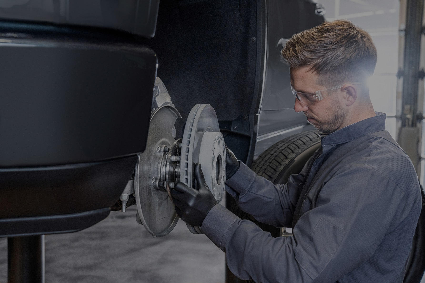 A Technician Replacing the Brake Rotors on a Lifted Vehicle.