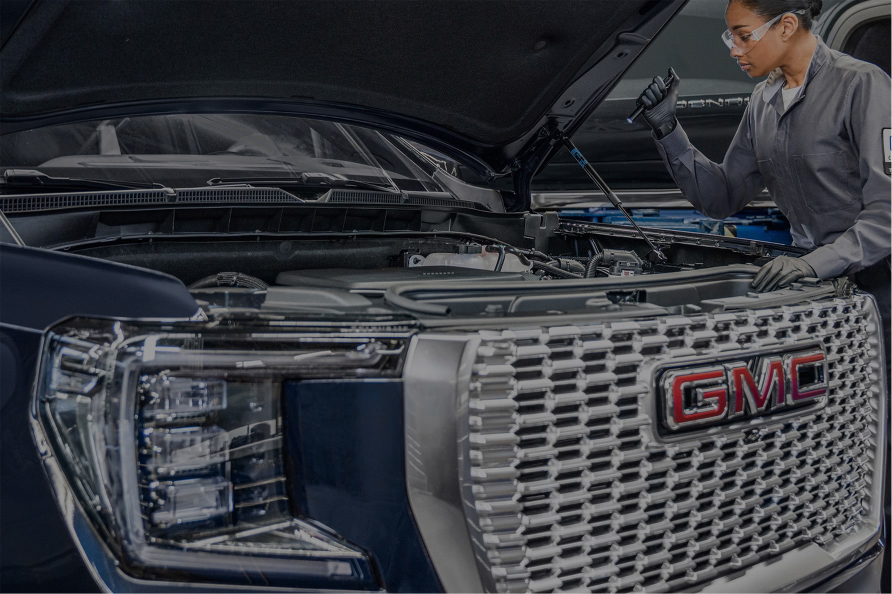 A Technician Working Under the Hood of a GMC Vehicle.