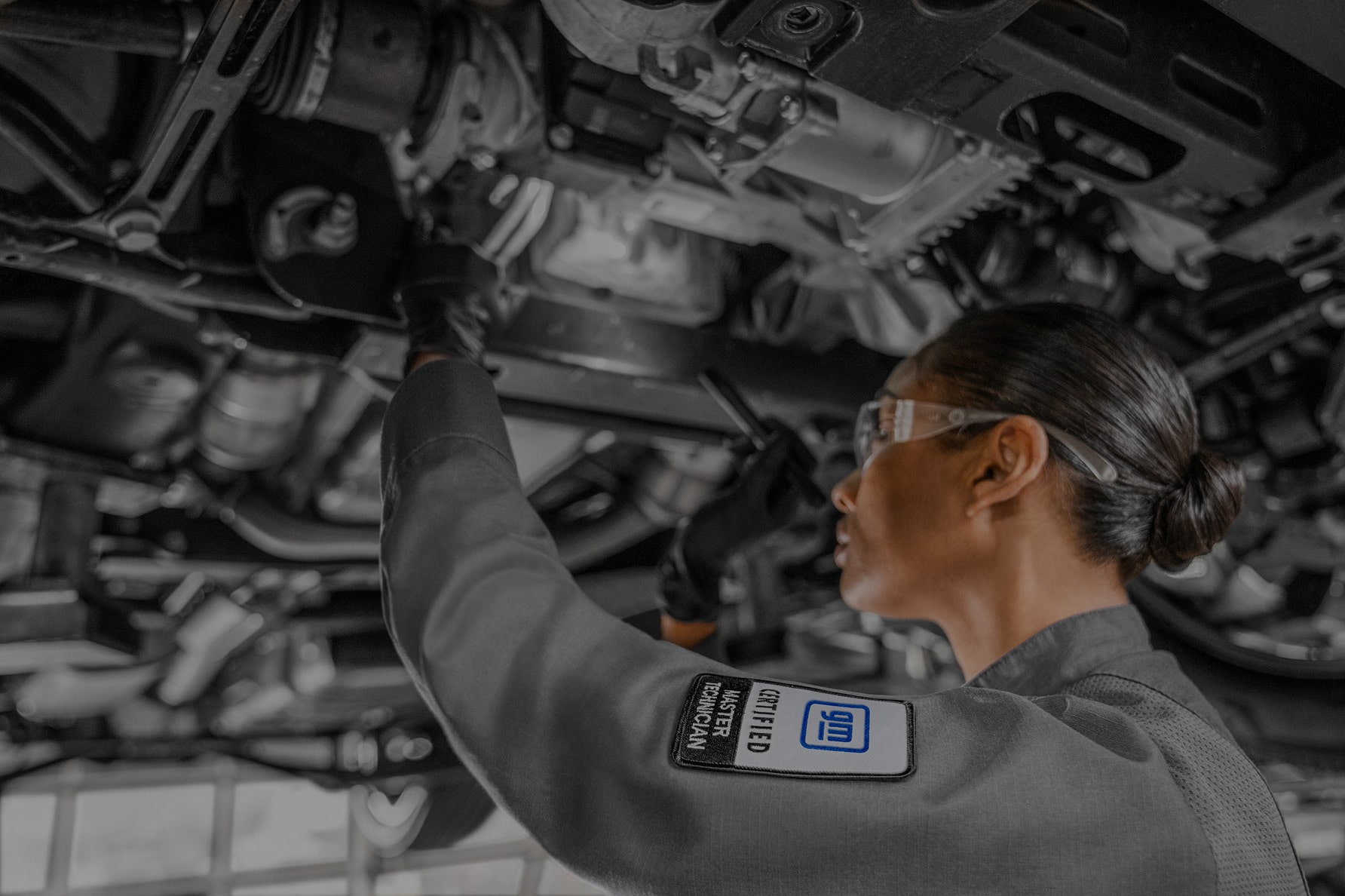 A Woman Technician Working Under a Lifted Vehicle.