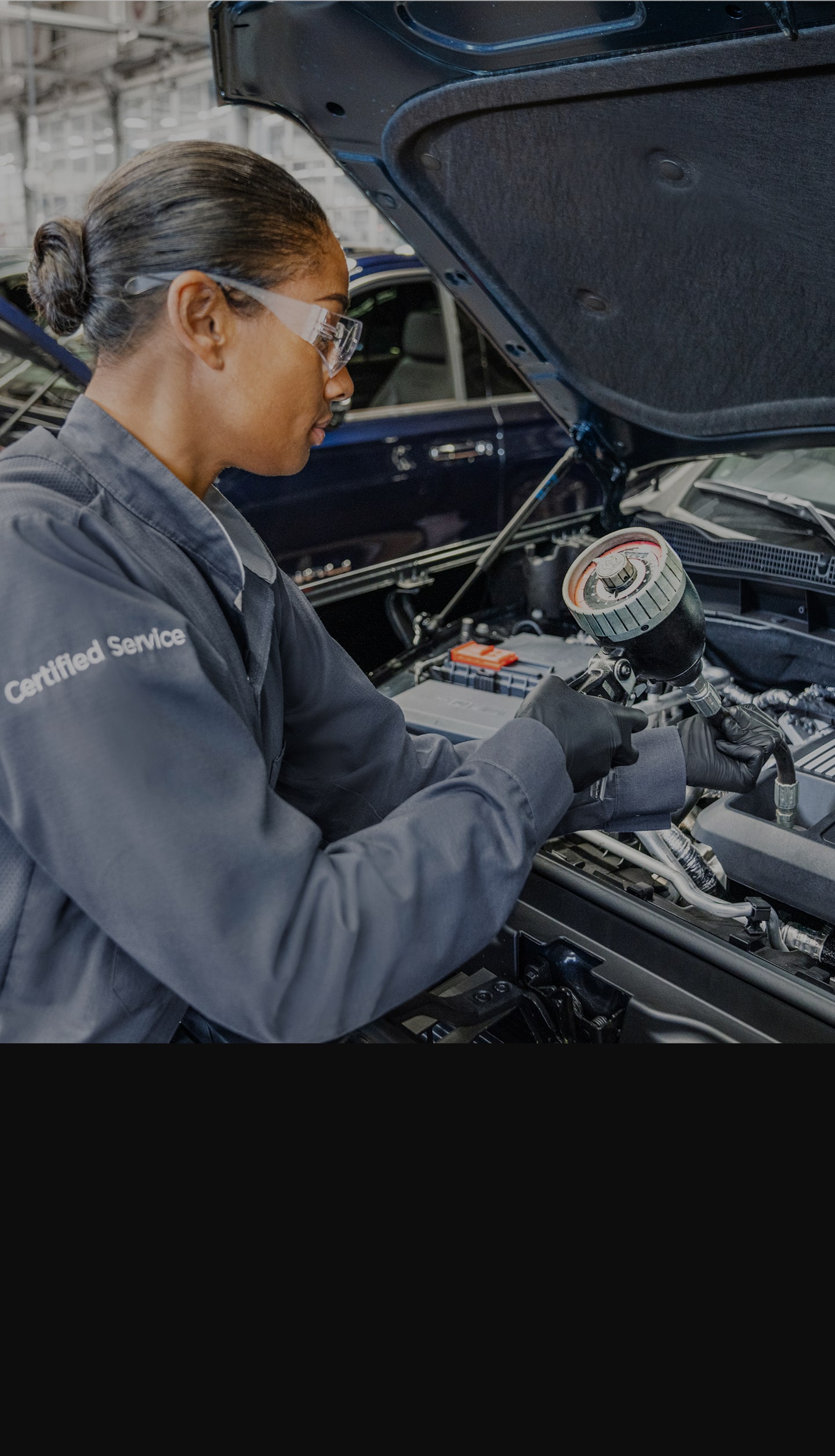 A Woman Technician Working Under the Hood of a Vehicle.
