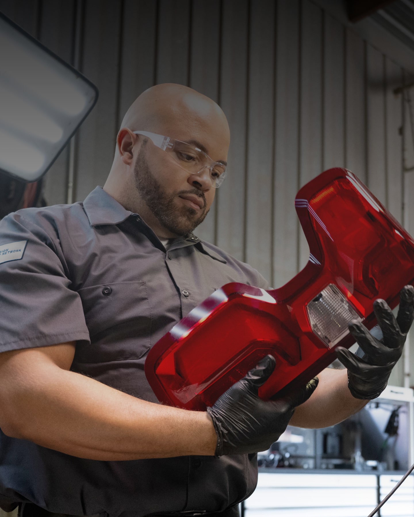 A Technician Working on a Vehicle Part with Gloves on and Eye Wear.