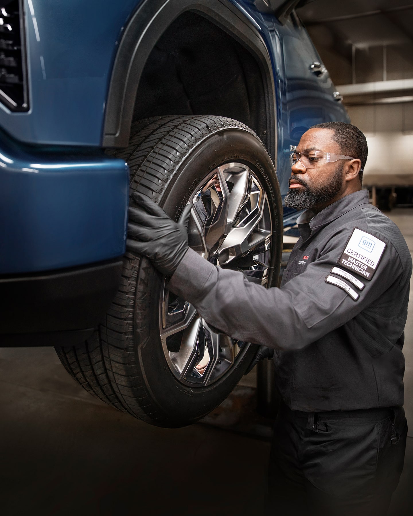 A Technician Working on a Vehicle Part with Gloves on and Eye Wear.