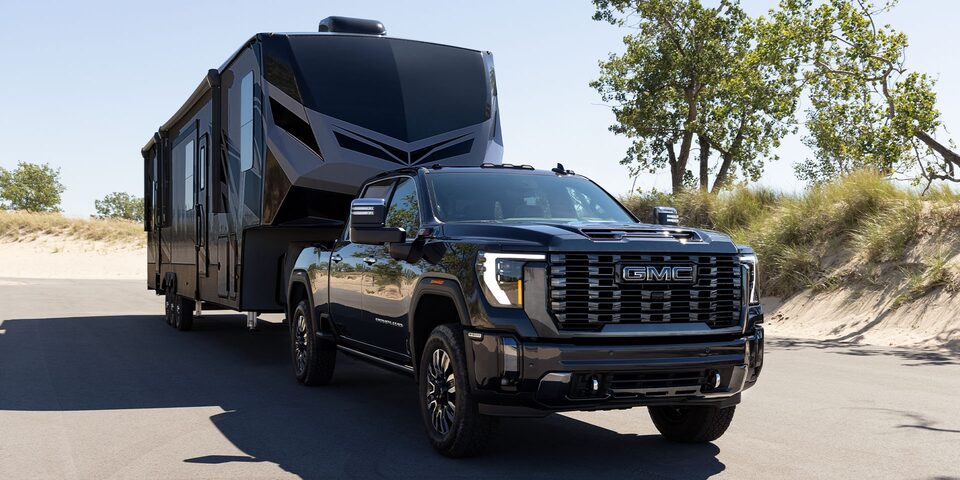 A Powerful GMC Vehicle Towing a Black Trailer On-Road