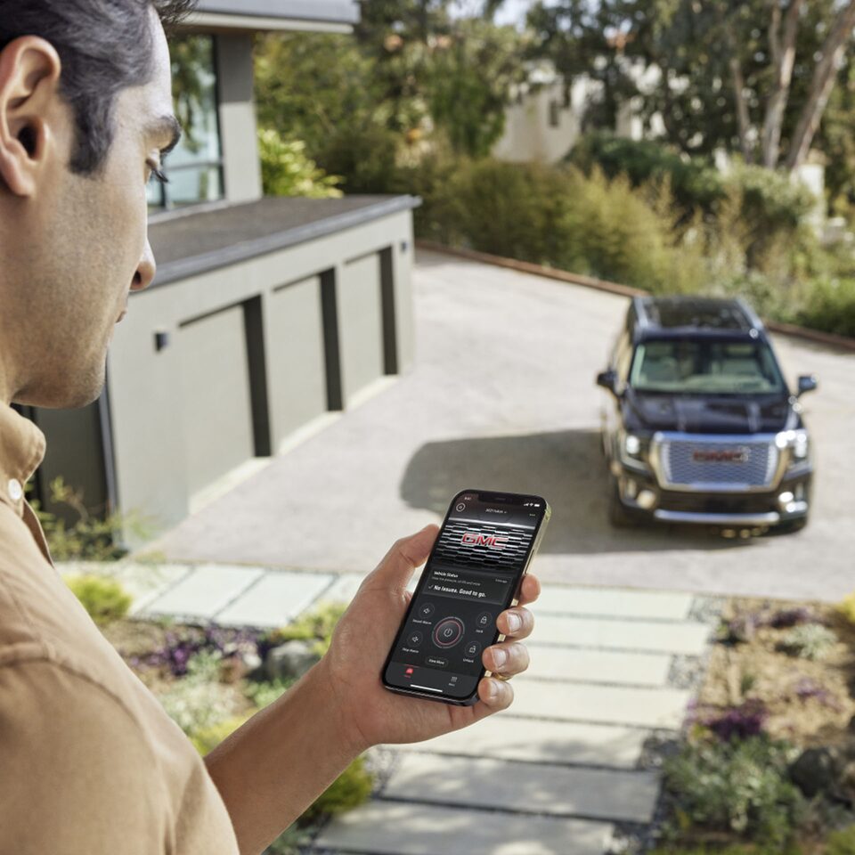 A Man Using the MYGMC Mobile App with His GMC Vehicle Parked