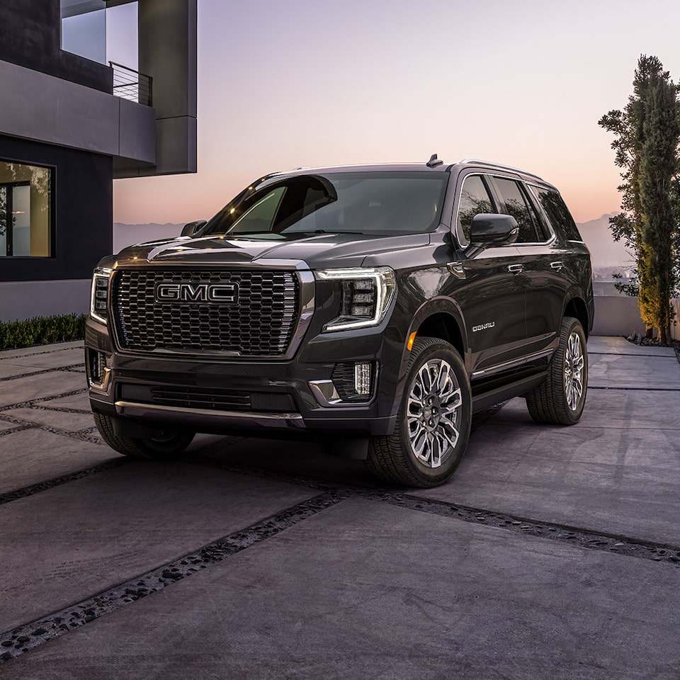 2024 GMC Yukon Denali Parked by a Home With a Sunset in the Background