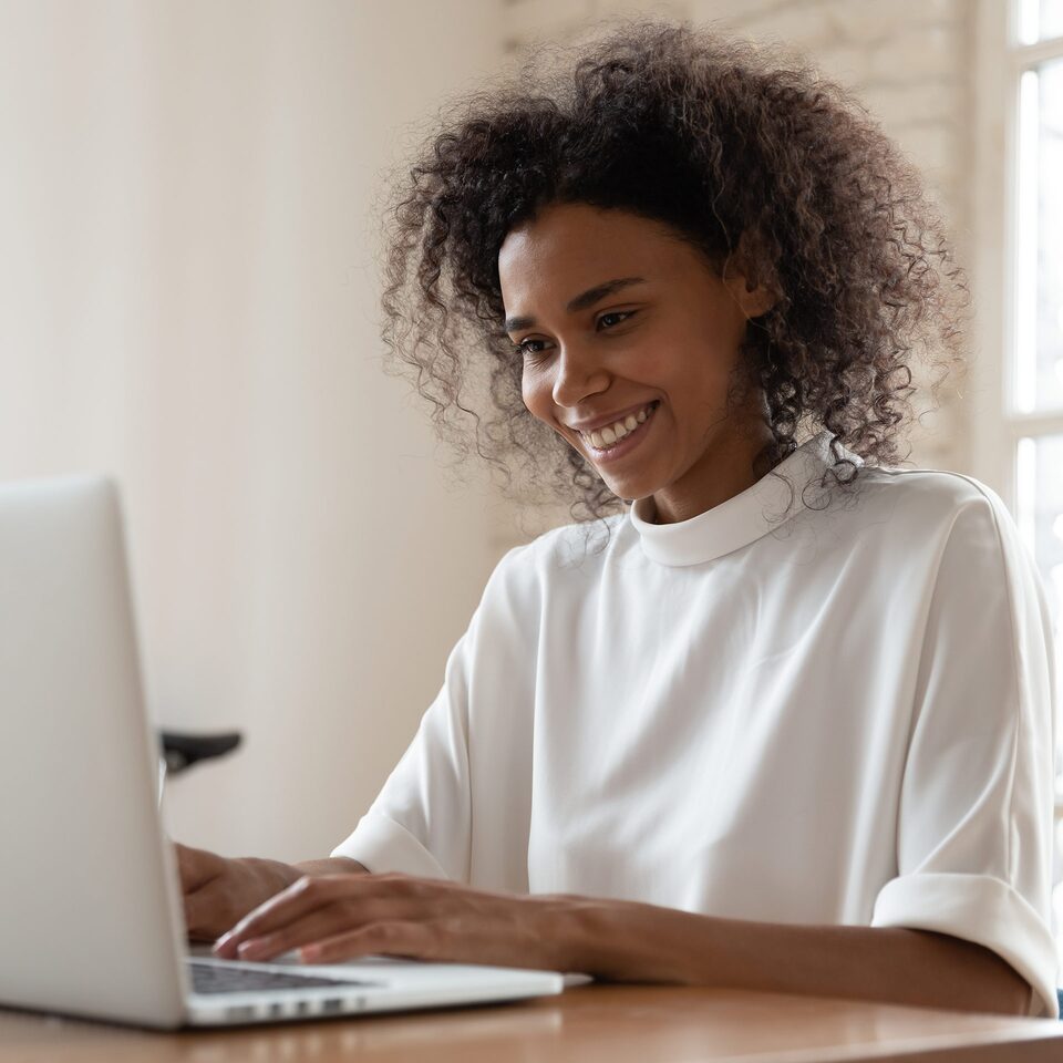 A Woman Using a Mac Laptop While Smiling and Sitting