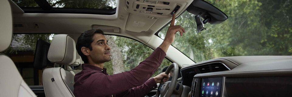 Man in the driver's seat of GMC vehicle pressing the OnStar button