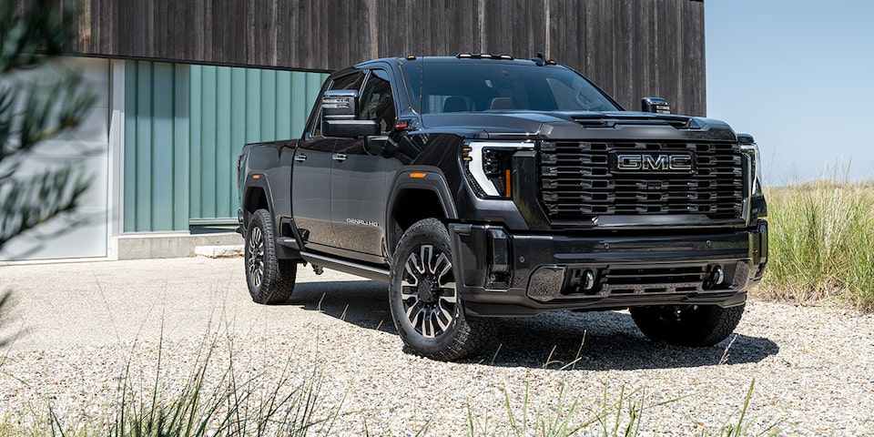The Black GMC Sierra HD Parked on Sand by a House