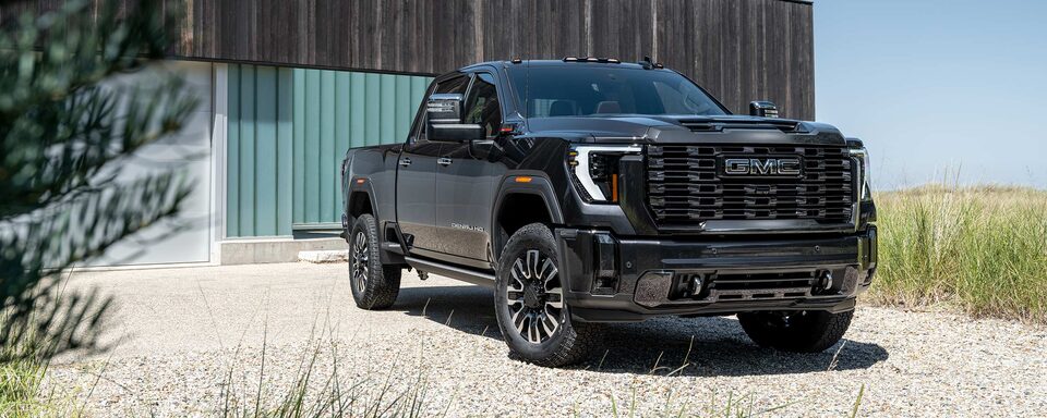 The Black GMC Sierra HD Parked on Sand by a House