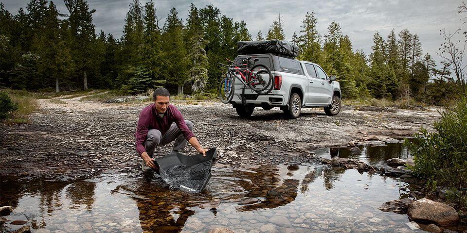 A Man Cleaning Floor Liners with a GMC Truck in the Background