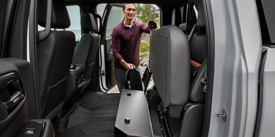 A Man Opening up the Rear Seats to Reveal Additional Cargo Space on a GMC Vehicle