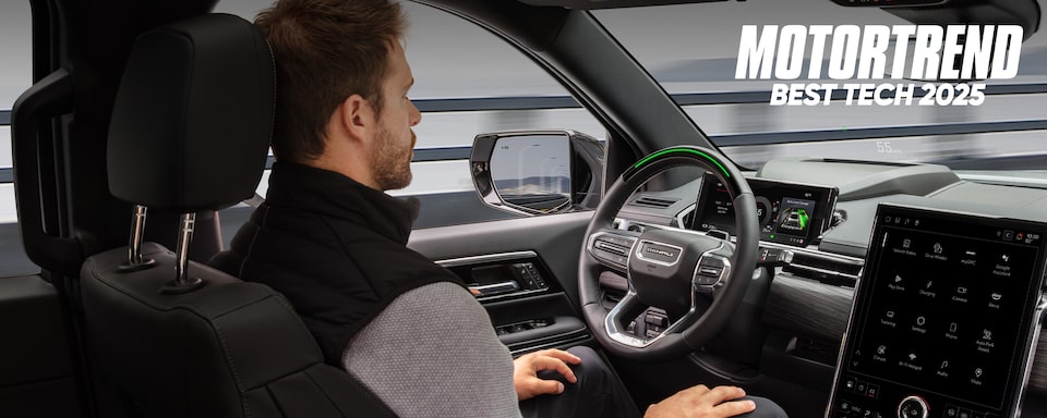 A Man Using Super Cruise in a GMC with Text Overlay: MOTORTREND BEST TECH 2025