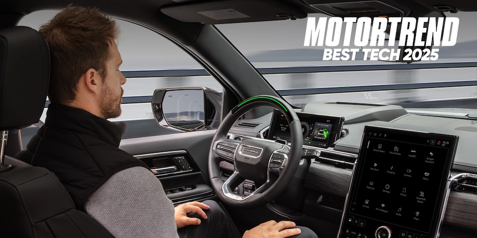 A Man Using Super Cruise in a GMC with Text Overlay: MOTORTREND BEST TECH 2025