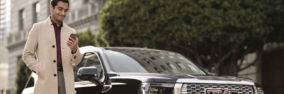 Man looking at smartphone with GMC vehicle in the background
