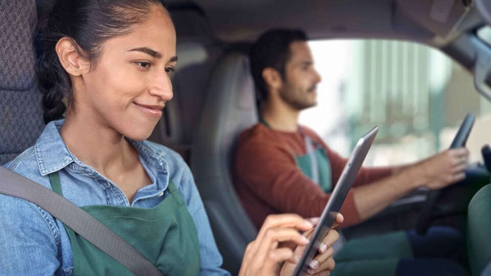 Woman in the passenger seat of GMC vehicle working on a tablet