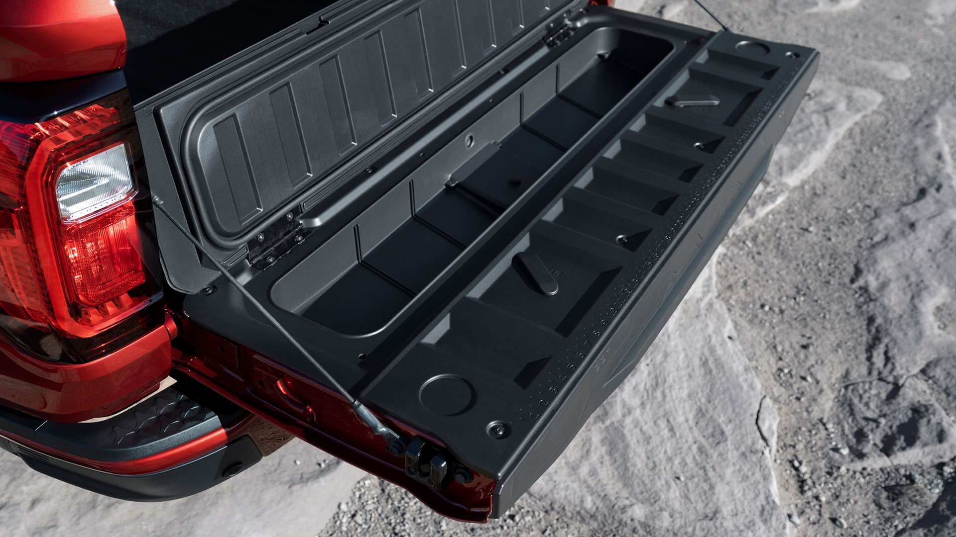 The Open Tailgate of a Red GMC Canyon AT4X Revealing an Integrated Storage Compartment