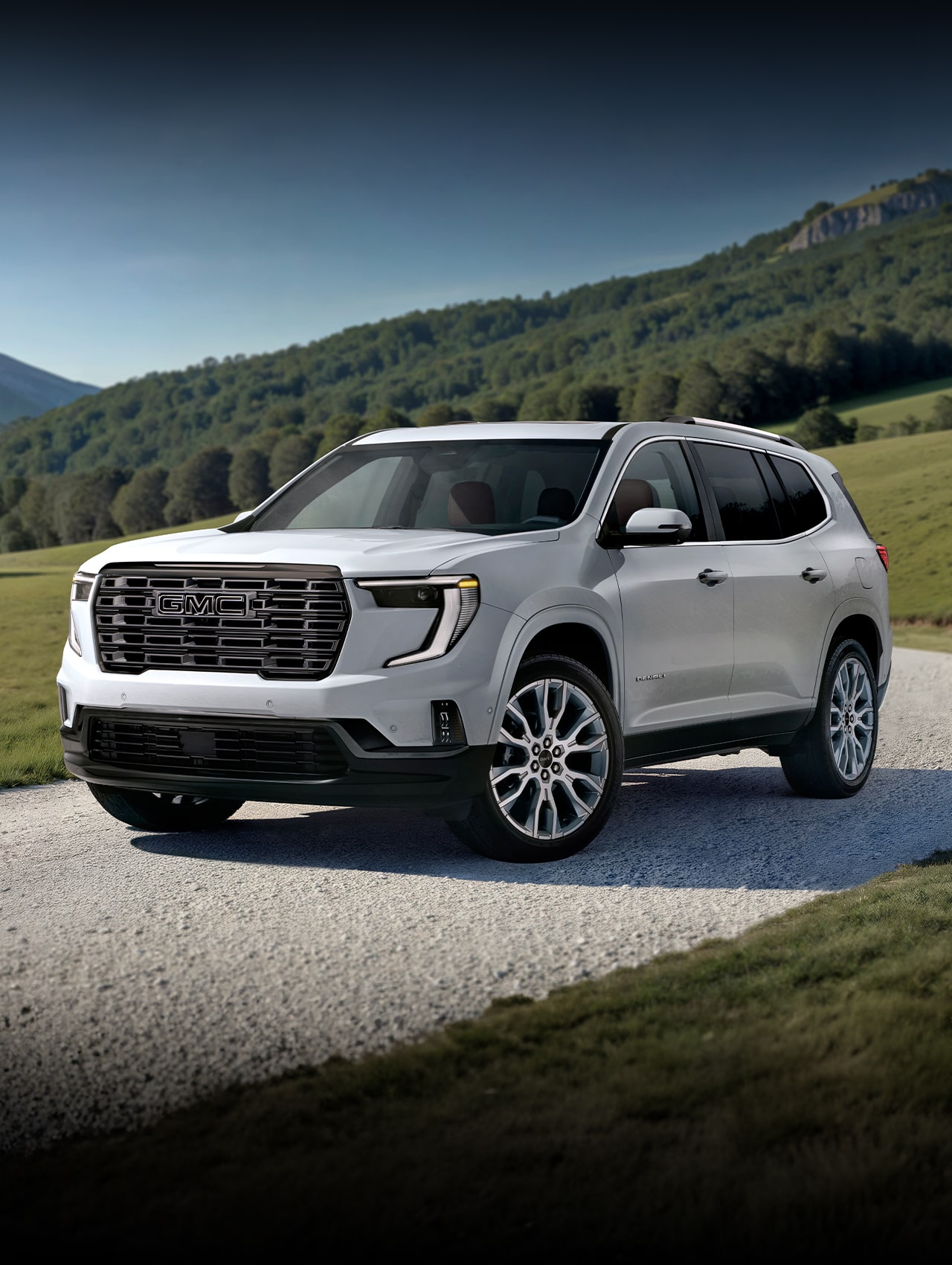 Front Three-Quarters View of the 2026 GMC Acadia Denali Ultimate Luxury Mid-Size SUV Driving Down a Long Driveway