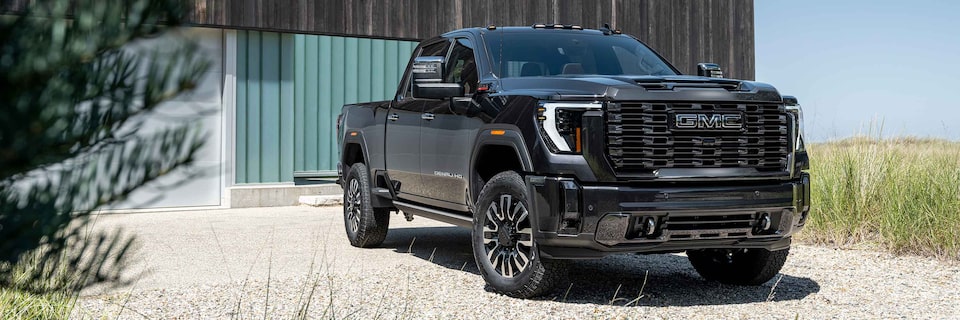 Front Three-Quarters View of a Black GMC Sierra HD Denali Ultimate Heavy-Duty Truck Parked Infront of a House