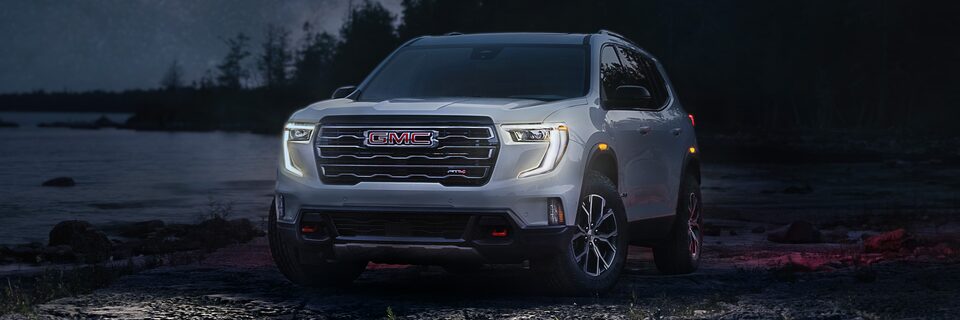 Front View of the GMC Acadia Mid-Size SUV with the Headlights on at Twilight