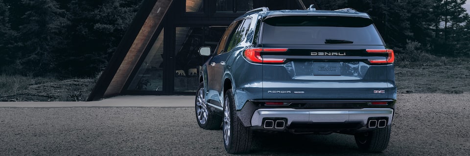 Rear View of a Blue GMC Acadia Denali Parked in the Woods in Front of the Beautiful Cabin