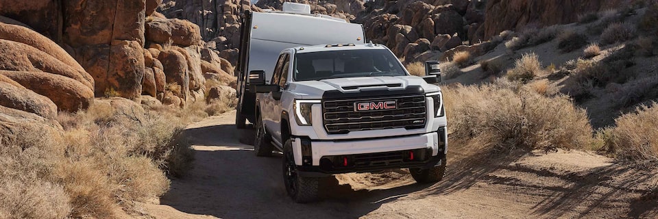 Front Three-Quarter View of a GMC Sierra HD AT4 Driving Down a Dirt Road