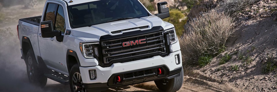 Front Three-Quarter View of a GMC Sierra HD AT4 Driving Down a Dirt Road