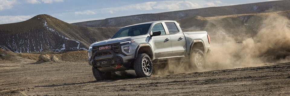 A GMC Canyon Off-Roading Through the Mountains Kicking Up Dust as it Speeds Across the Dusty Trail