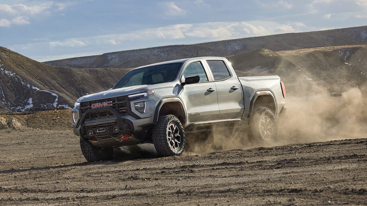 A Gray GMC Canyon AT4X Pickup Truck Kicking Up Dust While Driving Off-Road in a Desert Landscape