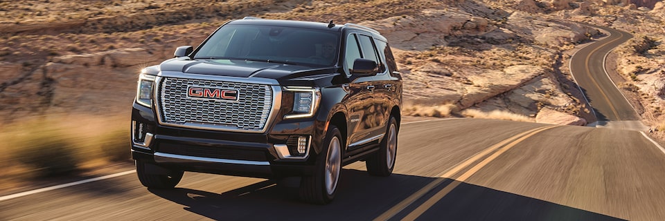 2021 GMC Yukon Denali driving on two-lane road through rugged terrain