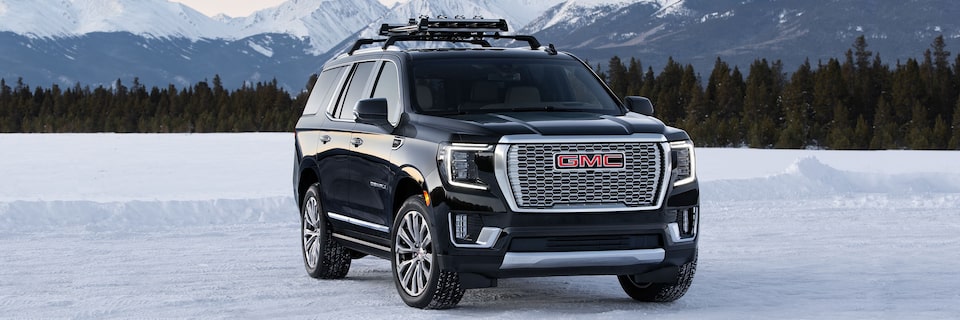 A All Black GMC Denali Parked Off-Road On Snow With Mountains in Background