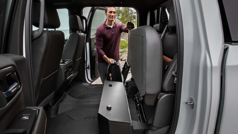 A Man Opening up the Rear Seats to Reveal Additional Cargo Space on a GMC Vehicle