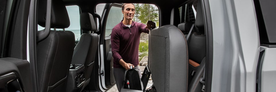 A Man Opening up the Rear Seats to Reveal Additional Cargo Space on a GMC Vehicle
