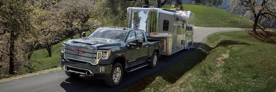 GMC Sierra HD Heavy Duty Truck Pulling an Enclosed Trailer with Green Rolling Hills in the Background