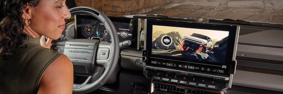 A Woman in the Driver Seat of a Hummer EV Looking at the Display Screen.