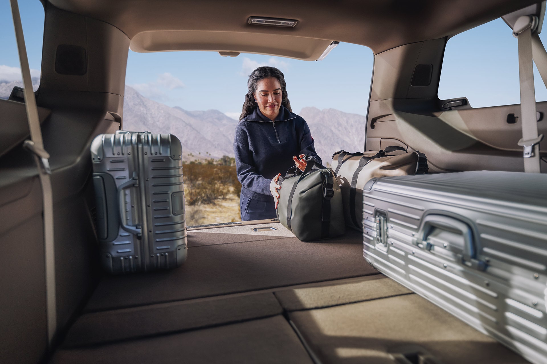 A Woman Packing Luggage and Bags in the Spacious Cargo Area of a GMC SUV with Mountain Scenery