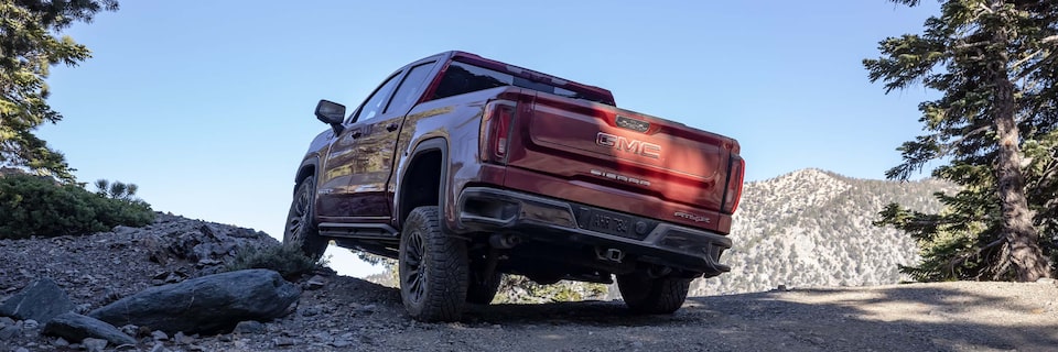 Rear View of the GMC Sierra AT4X Driving Over Rough Terrain in the Mountains