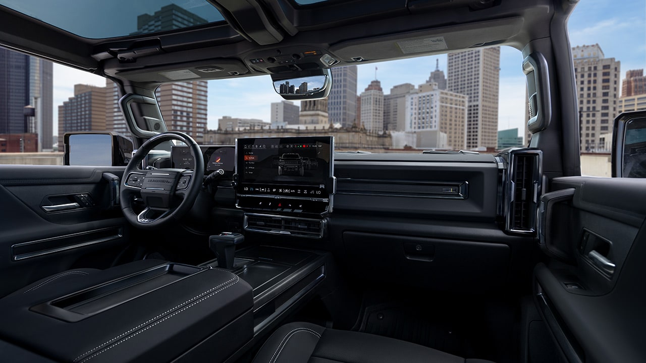 The Interior of a GMC HUMMER EV SUV Showing the Dashboard and a City Skyline Through the Windshield
