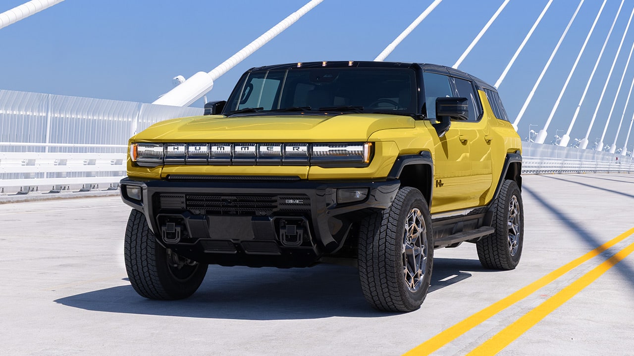 A Yellow GMC HUMMER EV SUV Parked on a Bridge Road With Yellow Stripes and Cable Stays