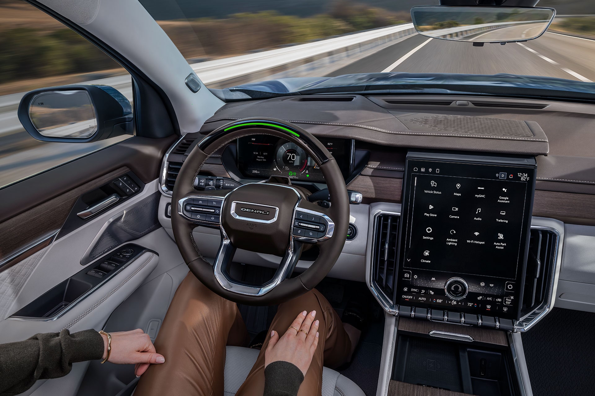 The Interior Driver's View of a GMC Denali with Hands on the Steering Wheel and a Large Infotainment Screen Showing Navigation