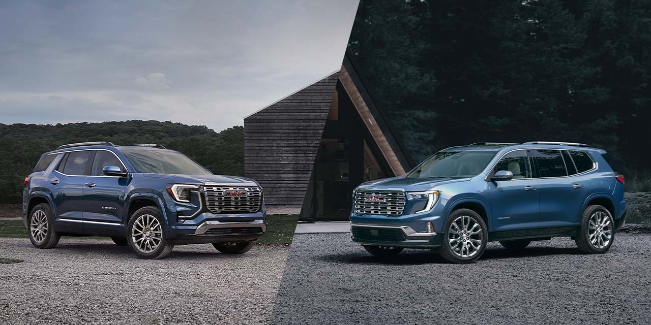 Two Blue GMC Acadia Denali SUVs, One on the Left and One on the Right, Parked on a Gravel Surface in Front of a Modern Building