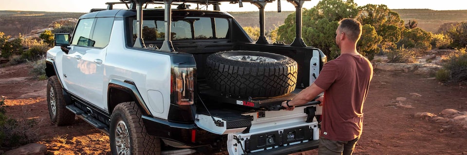 A Man Loading a Tire into his GMC HUMMER EV Truck Bed Using the Bedslide