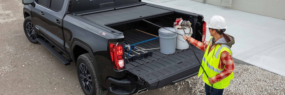 A Construction Worker Pulling the Truck Bed Cover Onto Their GMC Truck