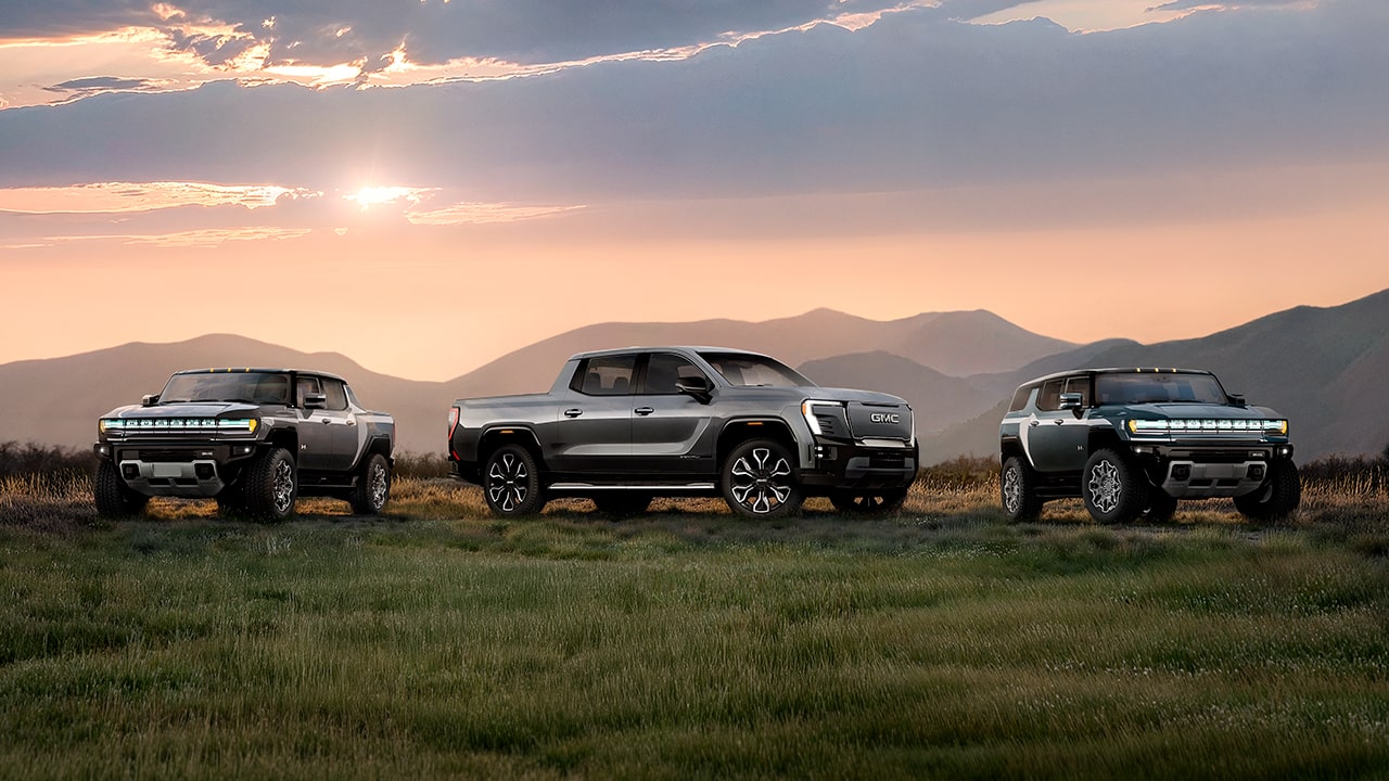 The GMC EV Line-up Parked in Front of a Mountain Range at Sunset