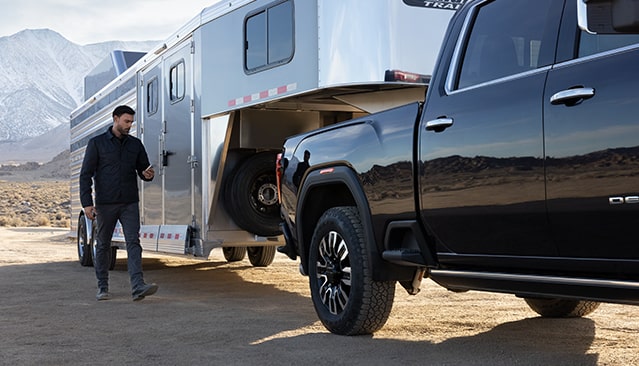A Man Walking to his Parked GMC Truck that is Towing a Trailer