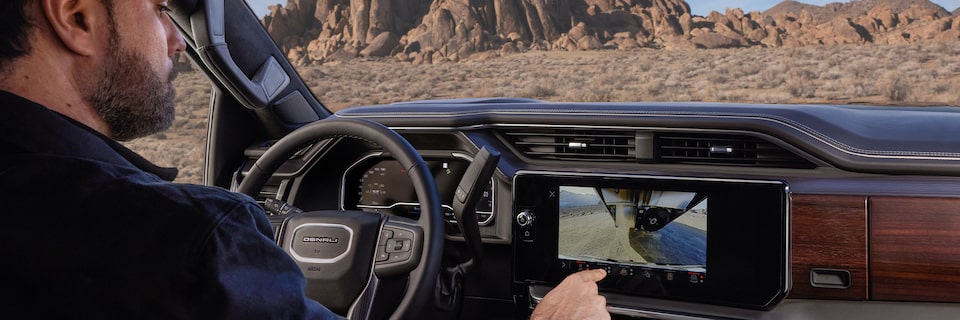 A Man Sitting in the Driver’s Seat Using the Infotainment Screen in a GMC Vehicle