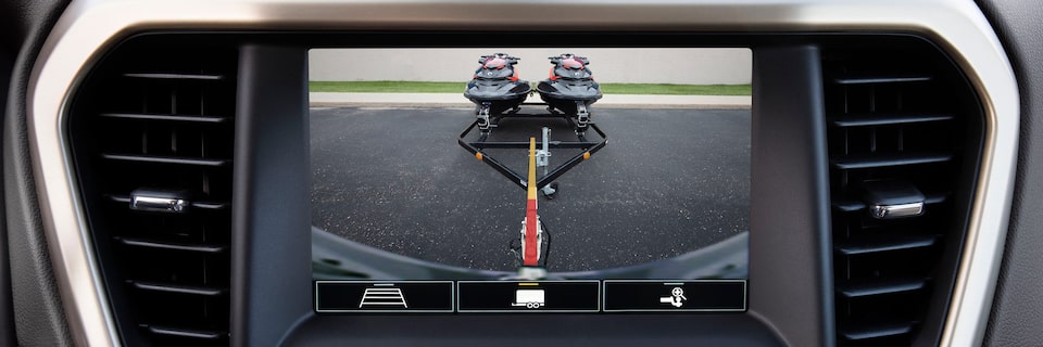 Focus View of a GMC Infotainment Screen Showing the Rear View Footage of a GMC SUV Towing Two Jet Skies