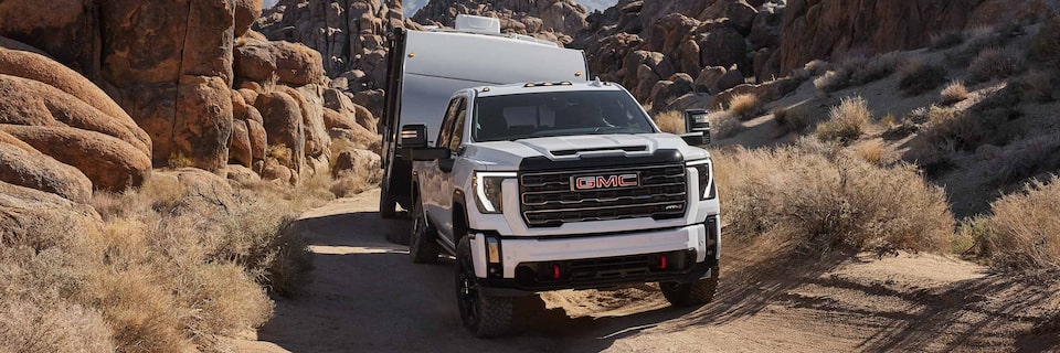 Three-Quarters View of a White GMC Pickup Truck Pulling a Trailer on a Rocky Road