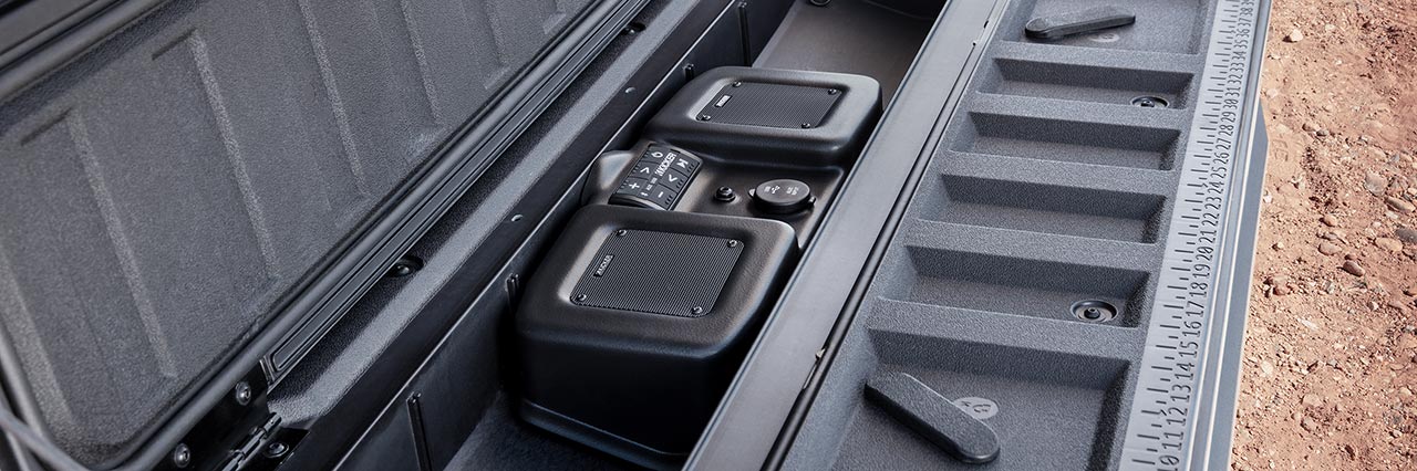 A Close-Up of a Truck Bed's Side Compartment with Built-in Kicker Speakers a Control Panel and a Ruler