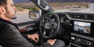 Profile View of a Man Using Super Cruise in his GMC While the Infotainment Screen Displays the Transparent Trailer View
